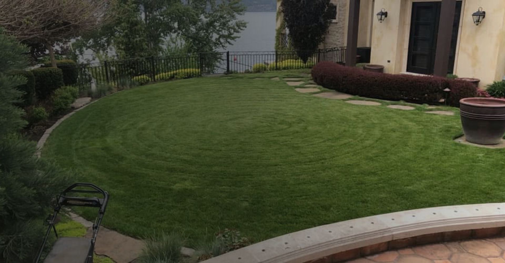 Immaculately landscaped residential yard with a concrete pathway lined with mulch, plants, and a beautifully edged green lawn.